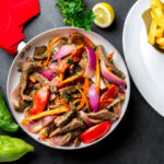 Close-up of Lomo Saltado, a Peruvian beef stir-fry with bell peppers and onions on a plate.
