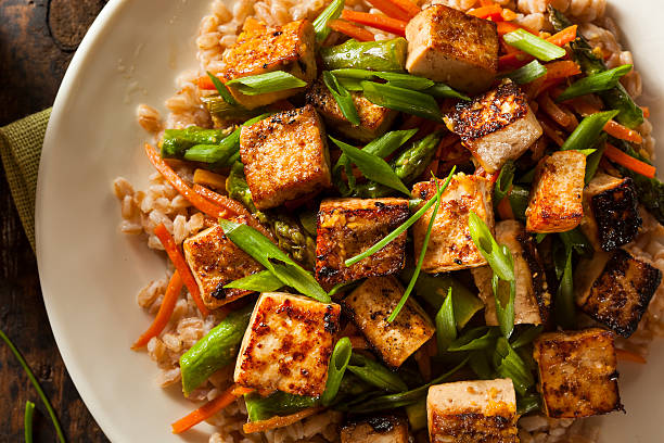 Close-up of Vegan Honey Garlic "Salmon" on a white plate, tofu pieces glazed with sesame seeds and green onions.